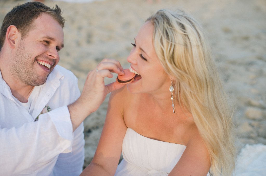 Photo groom feeds bride at the beach picnic